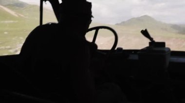 Orta Asya 'daki dağlarda eski araba kullanan bir adam.