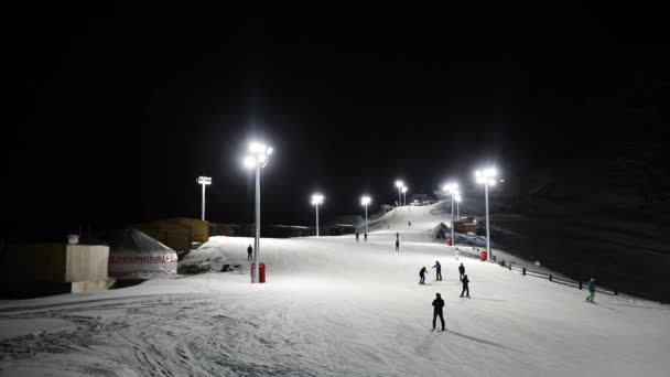 As pessoas andam na estância de esqui à noite. — Vídeo de Stock