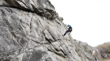 Atlet adam yüksek kayaya tırmanıyor