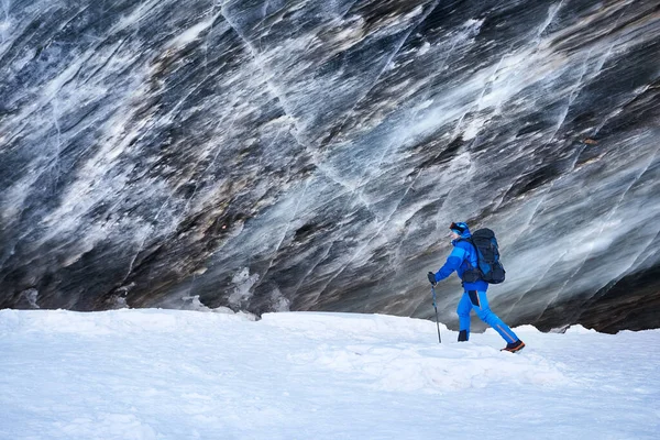 アルマトイ カザフスタンの雪で覆われた山の谷の美しい風景の氷河で氷の洞窟テクスチャの壁に近いバックパックと青の衣装で観光客 — ストック写真