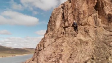 Atlet adam yüksek kayaya tırmanıyor