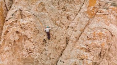 Atlet adam yüksek kayaya tırmanıyor
