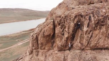 Atlet adam yüksek kayaya tırmanıyor