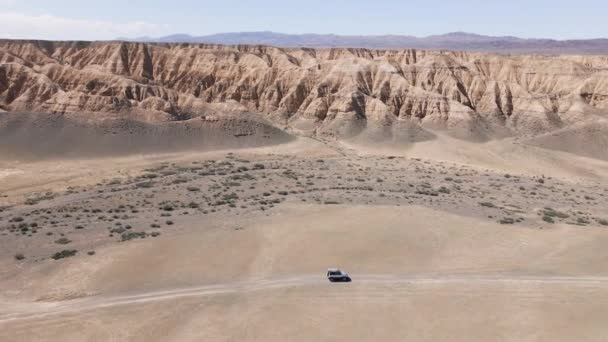 ドローンは、キャニオン砂漠の山々に乗ってオフロードカーを撮影 — ストック動画