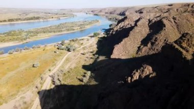 Kazakistan 'da gün batımında nehir ve dağların insansız hava aracı görüntüleri.