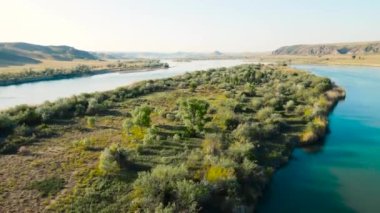 Kazakistan 'da gün batımında nehir ve dağların insansız hava aracı görüntüleri.