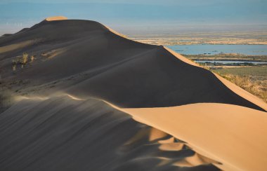 Almaty, Kazakistan yakınlarındaki ünlü Altyn Emel Milli Parkı 'nda Singing Sand Dunes Barkhan ve ili Nehri' nin günbatımı manzarası.