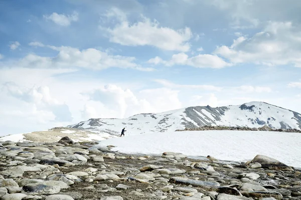 アルマトイ カザフスタンの青い空に対して美しい山の中の雪の丘の上を歩くバックパックを持つ男 — ストック写真