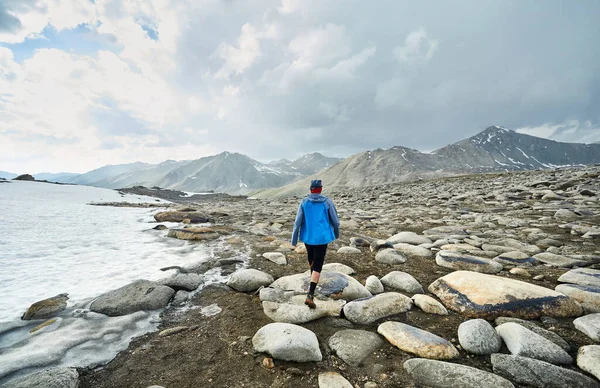 青いジャケットの男は曇りの空に対して美しい山の中の岩の谷を歩く — ストック写真