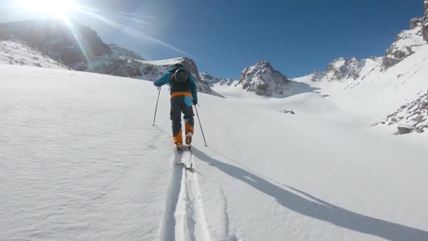 Man skiën bergop in hoge besneeuwde bergen — Stockvideo