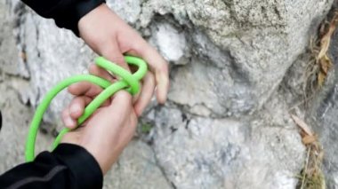 Atlet tırmanışçısı Kazakistan 'daki dağlarda kayaların yakınında yeşil bir iple bağlanmış.