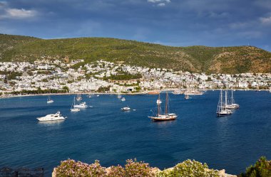 Kaleden Bodrum Sahili manzarası. Bodrum ilçesindeki tepelerde geleneksel beyaz evleri olan Ege Denizi 'nde yelkenli tekneler, yatlar