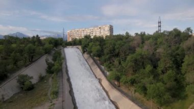 Almaty, Kazakistan 'da güneş doğarken Sairan Gölü yakınlarında gökdelenler ve dağ manzaralı nehrin görüntüsünü çektik.