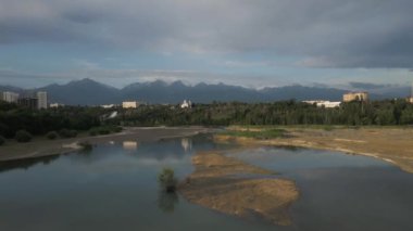 Sairan Gölü 'nün hava görüntüsü, Kazakistan, Almaty' de gün doğumunda dağ manzaralı gökdelenlerin yansıması.