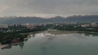 Sairan Gölü 'nün hava görüntüsü, Kazakistan, Almaty' de gün doğumunda dağ manzaralı gökdelenlerin yansıması.