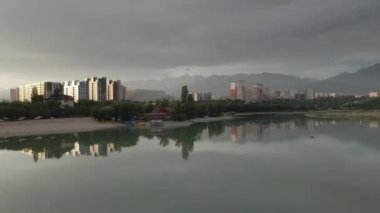Sairan Gölü 'nün hava görüntüsü, Kazakistan, Almaty' de gün doğumunda dağ manzaralı gökdelenlerin yansıması.