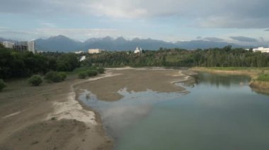 Sairan Gölü 'nün hava görüntüsü, Kazakistan, Almaty' de gün doğumunda dağ manzaralı gökdelenlerin yansıması.
