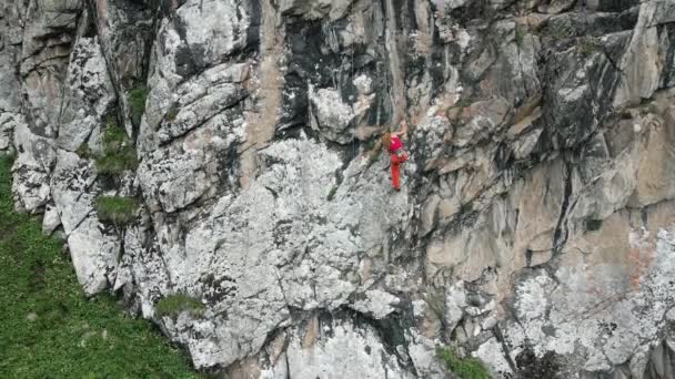 Снимок Беспилотника Сильной Женщины Красной Рубашке Взбирающейся Высокую Скалу Горах — стоковое видео