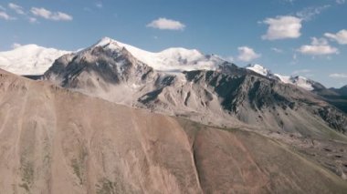 Aerial drone landscape reveal shot of snow summit and and rocky hills at mountain valley in Almaty Kazakhstan