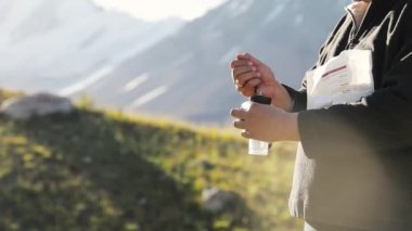 Göldeki kayalıklarda siyah öğütücüde taze kahve çekirdeklerini öğüten, kampta alternatif kahve demleyen adam. Açık havada piknikte sıcak içecek yapmak. Dağlarda trekking ve yürüyüş