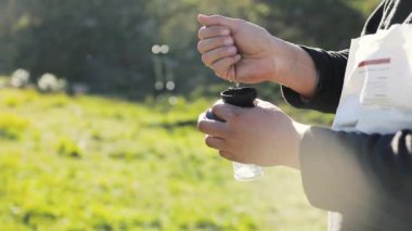 Göldeki kayalıklarda siyah öğütücüde taze kahve çekirdeklerini öğüten, kampta alternatif kahve demleyen adam. Açık havada piknikte sıcak içecek yapmak. Dağlarda trekking ve yürüyüş