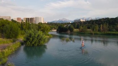 People swim at stand up paddle boards SUP in the mountain lake Sairan in city Almaty in Kazakhstan