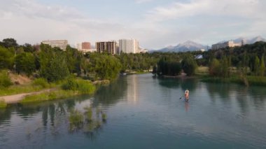 People swim at stand up paddle boards SUP in the mountain lake Sairan in city Almaty in Kazakhstan
