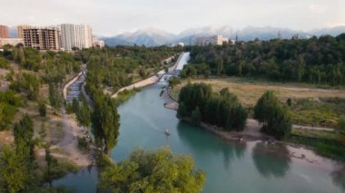 People swim at stand up paddle boards SUP in the mountain lake Sairan in city Almaty in Kazakhstan. Drone shot aerial outdoo activity