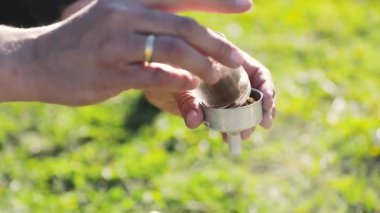 Man making coffee in moka pot from grinded fresh coffee at nature, brewing alternative coffee at camping. Making hot drink at picnic outdoors. Trekking and hiking in mountains