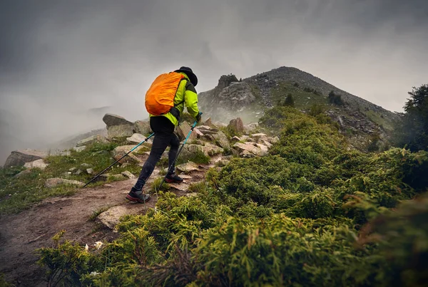 Człowiek Turysta Pomarańczowym Plecakiem Spacer Wzgórzu Skalnym Przed Mgłą Ciemnym — Zdjęcie stockowe