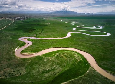 Dağ Vadisi, Kazakistan 'da gün batımında yeşil tepeli güzel manzaralı Kegen nehrinin insansız hava aracı görüntüsü. Otlakta beslenen at sürüsü