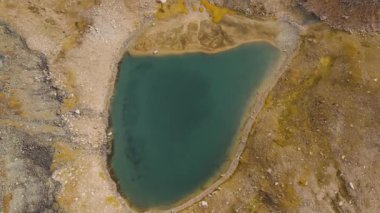 Almaty Kazakistan 'daki dağ vadisinde buzlu buzullu ve kayalık tepeli göl manzarası.