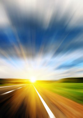 Blurred road and blue blurred sky with a shining sun clipart