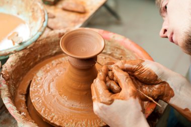Bir çömlekçinin elleri, çemberin üzerinde toprak kavanozu yaratıyor.