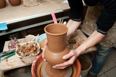 Bir çömlekçinin elleri, çemberin üzerinde toprak kavanozu yaratıyor.