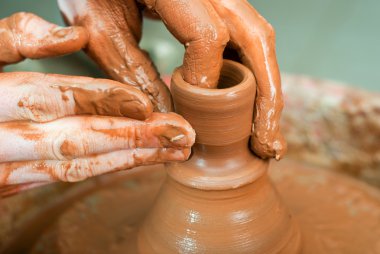 Bir çömlekçinin elleri, çemberin üzerinde toprak kavanozu yaratıyor.