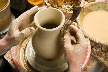 Bir çömlekçinin elleri, çemberin üzerinde toprak kavanozu yaratıyor.