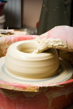 Bir çömlekçinin elleri, çemberin üzerinde toprak kavanozu yaratıyor.