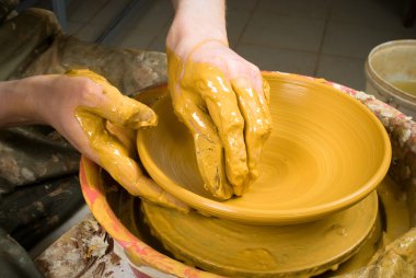 Bir çömlekçinin elleri, çemberin üzerinde toprak kavanozu yaratıyor.