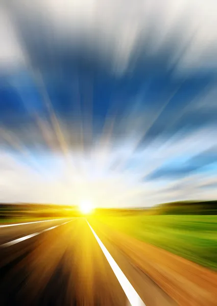 Blurred road and blue blurred sky with a shining sun — Stock Photo, Image