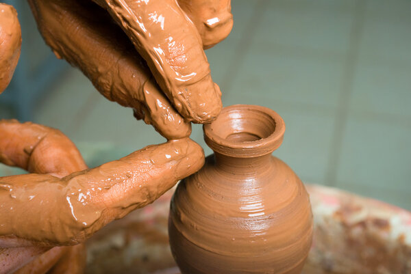 hands of a potter, creating an earthen jar on the circle