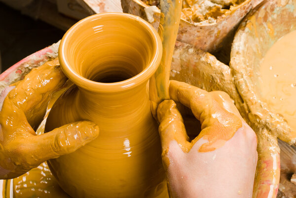 hands of a potter, creating an earthen jar of white clay