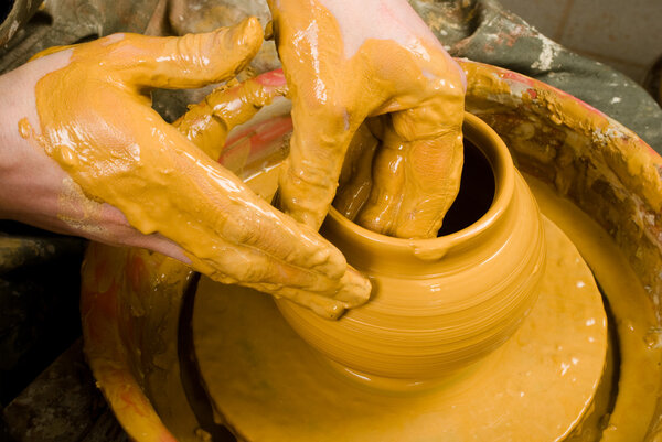 hands of a potter, creating an earthen jar of white clay