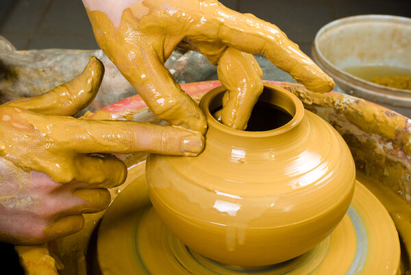 hands of a potter, creating an earthen jar on the circle