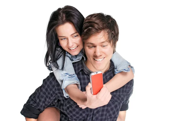 Sorridente giovane uomo tra le spalle la sua bella ragazza guardando il telefono — Foto Stock