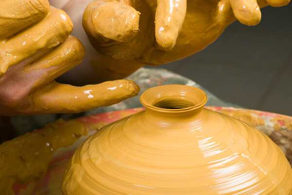 hands of a potter, creating an earthen jar of white clay