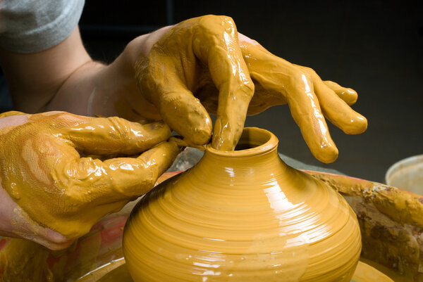hands of a potter, creating an earthen jar on the circle