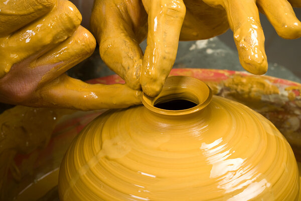 hands of a potter, creating an earthen jar on the circle