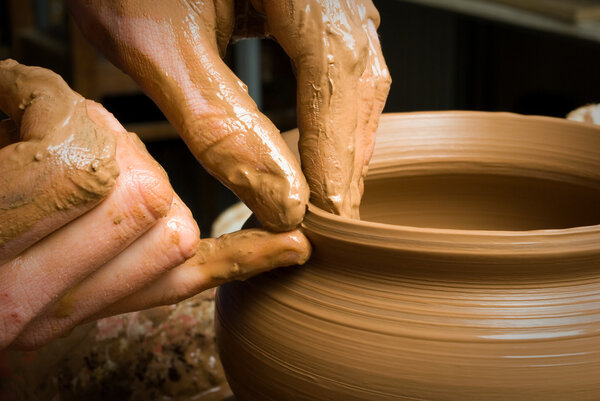 hands of a potter, creating an earthen jar on the circle