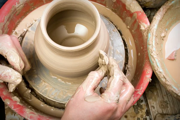 Hands of a potter, creating an earthen jar on the circle — Stock Photo, Image